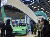 A visitor takes a picture of a Tesla taxi car at the Qatar Mowasalat Pavilion at the ConteQ Expo24 (Advanced Technology for Construction & S...