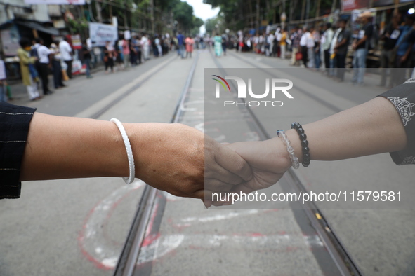 Teachers make a human chain during a protest against the rape and murder of a PGT woman doctor at the government-run R G Kar Medical College...