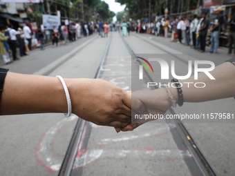 Teachers make a human chain during a protest against the rape and murder of a PGT woman doctor at the government-run R G Kar Medical College...