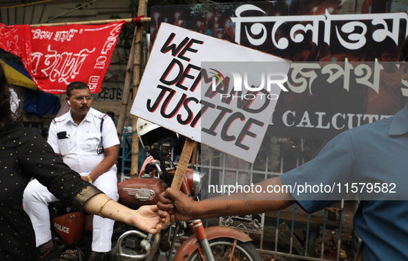 A police officer rests while teachers make a human chain during a protest against the rape and murder of a PGT woman doctor at the governmen...