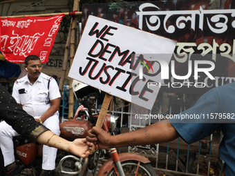 A police officer rests while teachers make a human chain during a protest against the rape and murder of a PGT woman doctor at the governmen...