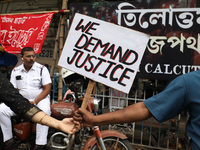 A police officer rests while teachers make a human chain during a protest against the rape and murder of a PGT woman doctor at the governmen...