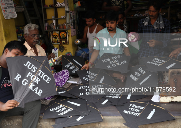 Kite-maker Ajit Dutta (L) displays kites printed with 'Justice for RG Kar' for sale at a shop to protest after the rape and murder of a PGT...