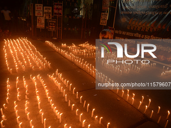 Former students of Ramkrishna Mission light candles as they take part in a protest to condemn the rape and murder of a young medic at RG Kar...