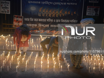 Former students of Ramkrishna Mission light candles as they take part in a protest to condemn the rape and murder of a young medic at RG Kar...