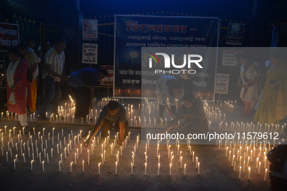 Former students of Ramkrishna Mission light candles as they take part in a protest to condemn the rape and murder of a young medic at RG Kar...