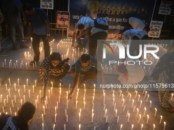 Former students of Ramkrishna Mission light candles as they take part in a protest to condemn the rape and murder of a young medic at RG Kar...