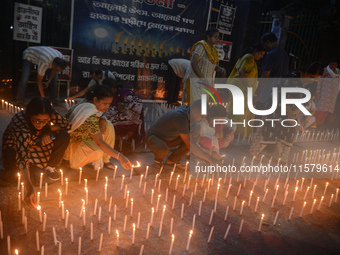 Former students of Ramkrishna Mission light candles as they take part in a protest to condemn the rape and murder of a young medic at RG Kar...