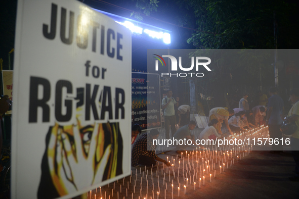 Former students of Ramkrishna Mission light candles as they take part in a protest to condemn the rape and murder of a young medic at RG Kar...