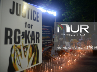 Former students of Ramkrishna Mission light candles as they take part in a protest to condemn the rape and murder of a young medic at RG Kar...