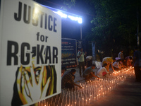 Former students of Ramkrishna Mission light candles as they take part in a protest to condemn the rape and murder of a young medic at RG Kar...