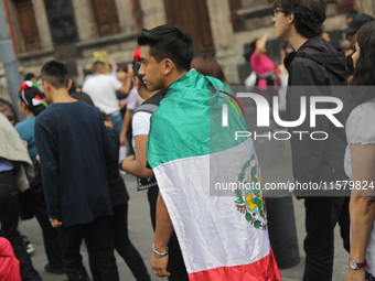 A person wears a Mexican flag on their back while attending the celebration of the 214th Anniversary of Mexico's Independence Day in the mai...