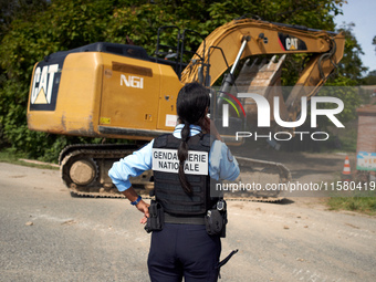 A gendarme looks at an excavator entering the 'Verger' to destroy it. After months of negotiations and pressures from NGE/Atosca, and two in...