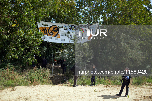 Gendarmes stand guard near the 'Verger' ZAD. The banner reads 'A69, the highway stops there'. After months of negotiations and pressures fro...