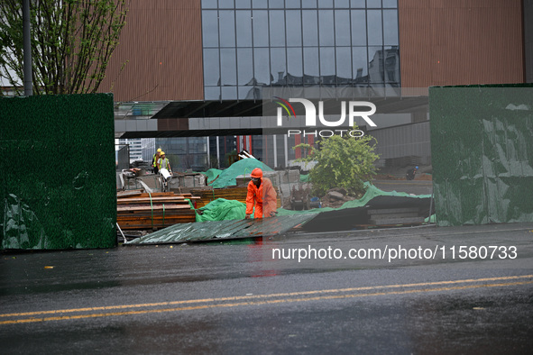 Workers clean up after a fence is blown down at a construction site in Nanjing, Jiangsu province, China, on September 17, 2024. 