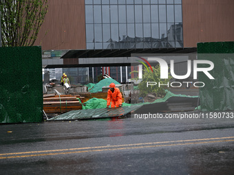 Workers clean up after a fence is blown down at a construction site in Nanjing, Jiangsu province, China, on September 17, 2024. (