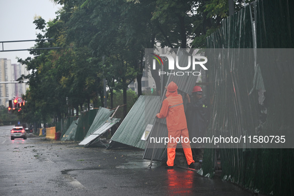 Workers clean up after a fence is blown down at a construction site in Nanjing, Jiangsu province, China, on September 17, 2024. 