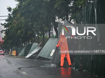 Workers clean up after a fence is blown down at a construction site in Nanjing, Jiangsu province, China, on September 17, 2024. (