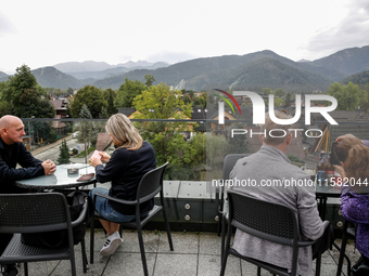 People in warm jackets watch a panorama view on Tatra mountains on a landmark Krupowki Street in the center of Zakopane, a popular Tatra mou...