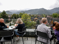 People in warm jackets watch a panorama view on Tatra mountains on a landmark Krupowki Street in the center of Zakopane, a popular Tatra mou...