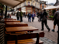 People in warm jackets walk on a landmark Krupowki Street as outdoor restaurants are empty in the center of Zakopane, a popular Tatra mounta...