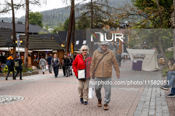 Pensioners walk on a landmark Krupowki Street in the center of Zakopane, a popular Tatra mountain holiday resort as Autumn cold weather star...