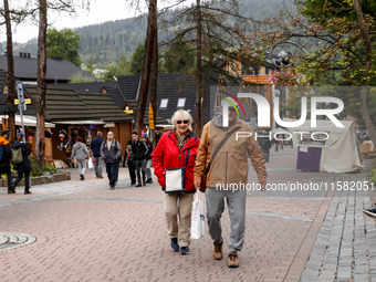 Pensioners walk on a landmark Krupowki Street in the center of Zakopane, a popular Tatra mountain holiday resort as Autumn cold weather star...