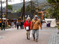 Pensioners walk on a landmark Krupowki Street in the center of Zakopane, a popular Tatra mountain holiday resort as Autumn cold weather star...