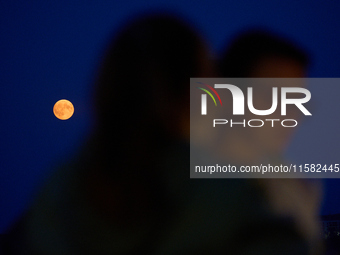 People are seen dining out as the Harvest Moon is seen in the night sky over Frankfurt an der Oder, Germany on 17 September, 2024. (