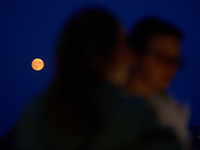 People are seen dining out as the Harvest Moon is seen in the night sky over Frankfurt an der Oder, Germany on 17 September, 2024. (