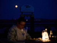 People are seen dining out as the Harvest Moon is seen in the night sky over Frankfurt an der Oder, Germany on 17 September, 2024. (