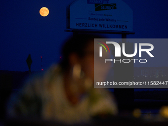 People are seen dining out as the Harvest Moon is seen in the night sky over Frankfurt an der Oder, Germany on 17 September, 2024. (