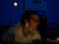 People are seen dining out as the Harvest Moon is seen in the night sky over Frankfurt an der Oder, Germany on 17 September, 2024. (