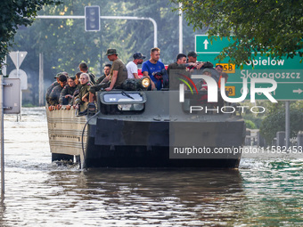 Residents are being evacuated on a military amphibious vehicle by emergency workers after Nysa Klodzka river flooded town of Lewin Brzeski i...