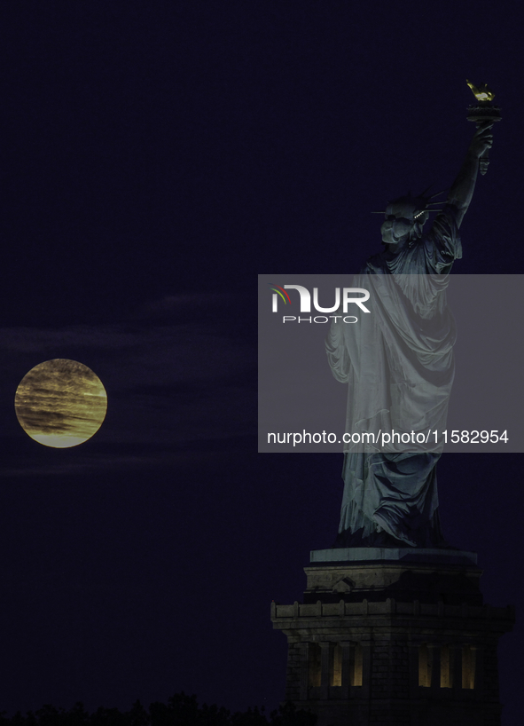 A partial lunar eclipse and supermoon occur in New York, United States, on September 17, 2024, as captured from Liberty Park in New Jersey....