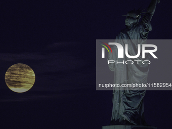 A partial lunar eclipse and supermoon occur in New York, United States, on September 17, 2024, as captured from Liberty Park in New Jersey....