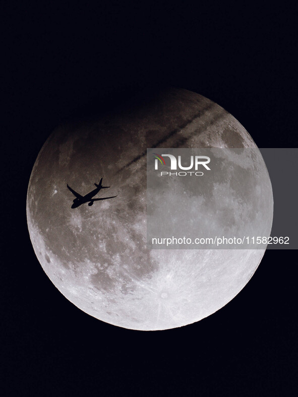 A TAP Air Portugal flight (TAP238) from San Francisco to Lisbon flies in front of the partially eclipsed Super Moon as seen from the ground...