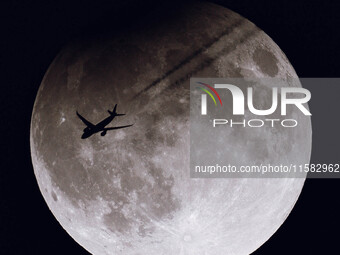 A TAP Air Portugal flight (TAP238) from San Francisco to Lisbon flies in front of the partially eclipsed Super Moon as seen from the ground...