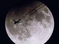 A TAP Air Portugal flight (TAP238) from San Francisco to Lisbon flies in front of the partially eclipsed Super Moon as seen from the ground...