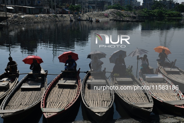 Boatmen hold umbrellas under the hot sun as they wait for passengers at the old Buriganga River channel in Dhaka, Bangladesh, on September 1...