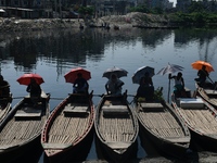 Boatmen hold umbrellas under the hot sun as they wait for passengers at the old Buriganga River channel in Dhaka, Bangladesh, on September 1...