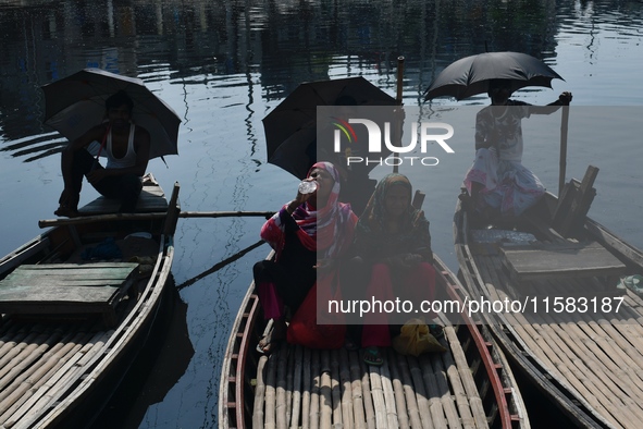 Boatmen hold umbrellas under the hot sun as they wait for passengers at the old Buriganga River channel in Dhaka, Bangladesh, on September 1...