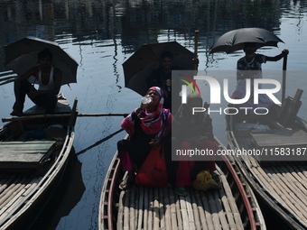 Boatmen hold umbrellas under the hot sun as they wait for passengers at the old Buriganga River channel in Dhaka, Bangladesh, on September 1...