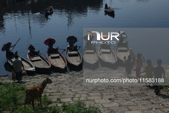 Boatmen hold umbrellas under the hot sun as they wait for passengers at the old Buriganga River channel in Dhaka, Bangladesh, on September 1...