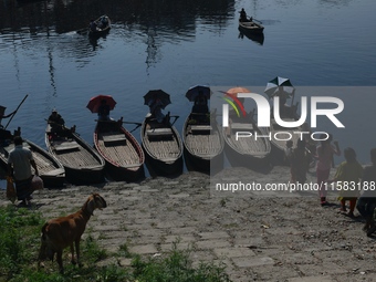 Boatmen hold umbrellas under the hot sun as they wait for passengers at the old Buriganga River channel in Dhaka, Bangladesh, on September 1...