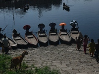 Boatmen hold umbrellas under the hot sun as they wait for passengers at the old Buriganga River channel in Dhaka, Bangladesh, on September 1...