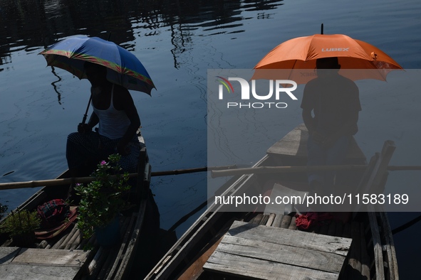 Boatmen hold umbrellas under the hot sun as they wait for passengers at the old Buriganga River channel in Dhaka, Bangladesh, on September 1...