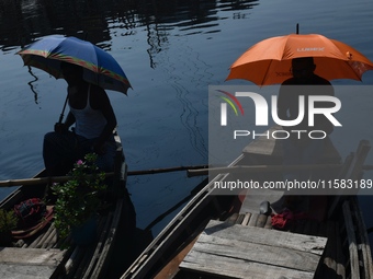 Boatmen hold umbrellas under the hot sun as they wait for passengers at the old Buriganga River channel in Dhaka, Bangladesh, on September 1...