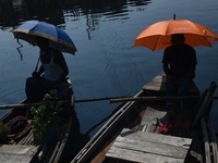 Boatmen hold umbrellas under the hot sun as they wait for passengers at the old Buriganga River channel in Dhaka, Bangladesh, on September 1...