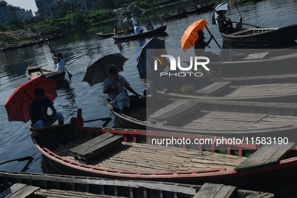 Boatmen hold umbrellas under the hot sun as they wait for passengers at the old Buriganga River channel in Dhaka, Bangladesh, on September 1...